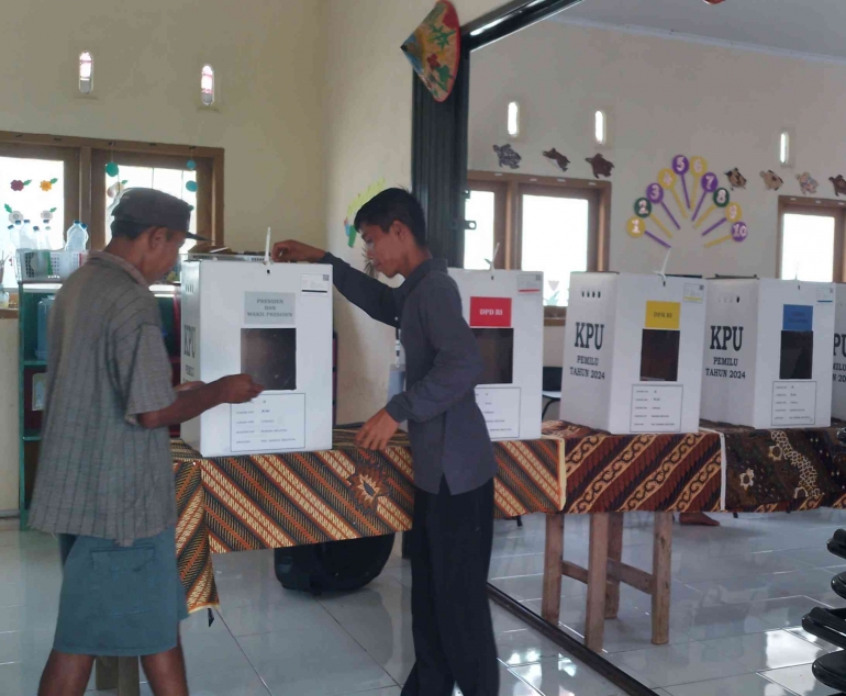 Petugas KPPS Membantu Pemilih Memasukan Surat Suara ke Bilik Suara di TPS 18 Dusun Suka Maju. (Sumber: Agustian Deny Ardiansyah/Dokpri)