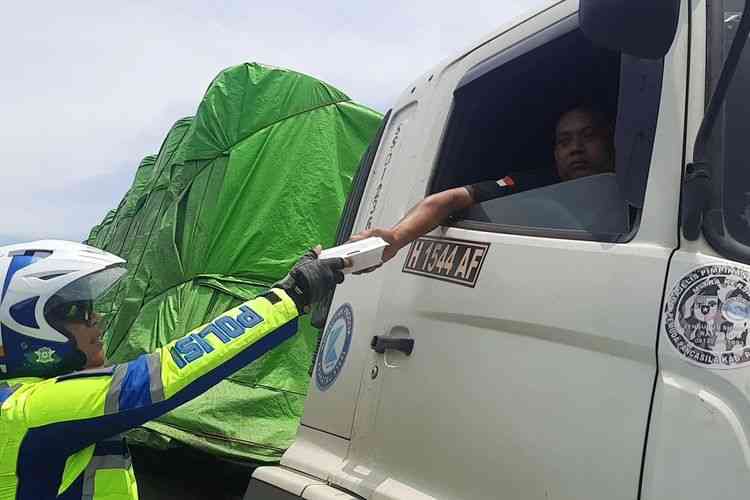 Polisi membagikan nasi bungkus ke sopir truk yang terjebak macet di jalan raya Pati-Rembang|dok. Kompas.com/Aria Rusta Yuli Pradana