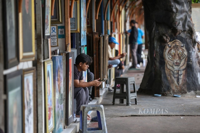 Seorang pelukis menunggu pelanggan di salah satu kios di Jalan Gedung Kesenian, Sawah Besar, Jakarta Pusat (KOMPAS/Fakhri Fadlurrohman)