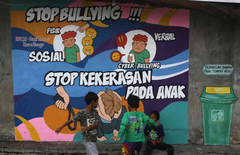 Anak-anak bermain dengan latar mural untuk mencegah perundungan dan kekerasan (Sumber:  KOMPAS/RIZA FATHONI) 
