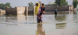 Seorang ibu dan anaknya sedang berjalan dalam banjir di Pakistan. | Sumber: news.un.org
