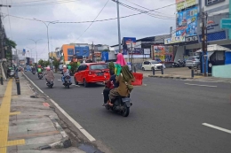 Anak berdiri di atas jok saat sepeda motor melaju di jalan raya (foto: widikurniawan)
