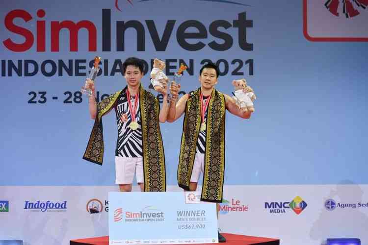 Kevin Sanjaya Sukamuljo (kiri) dan Marcus Fernaldi Gideon (kanan) saat mengangkat trofi juara Indonesia Open 2021 di Bali International Convention Centre, Minggu (28/11/2021). (DOK. Humas PBSI via kompas.com)