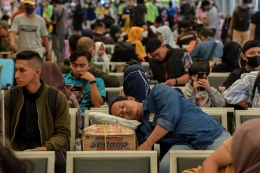 ilustrasi: Seorang calon penumpang tertidur saat menunggu jadwal pemberangkatan kereta di Stasiun Pasar Senen, Jakarta Pusat (11/4/2023). (Foto: KOMPAS/FAKHRI FADLURROHMAN)