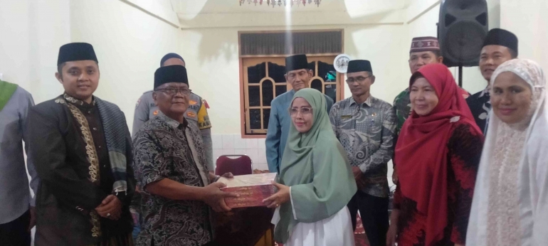 Sekdis DPPKB Padang Pariaman menyerahkan bingkisan Quran ke pengurus Surau Korong Padang Baru. (foto dokpri)