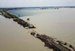 Memperbaiki tanggul Sungai Wulan yang jebol (KOMPAS/P RADITYA MAHENDRA YASA)