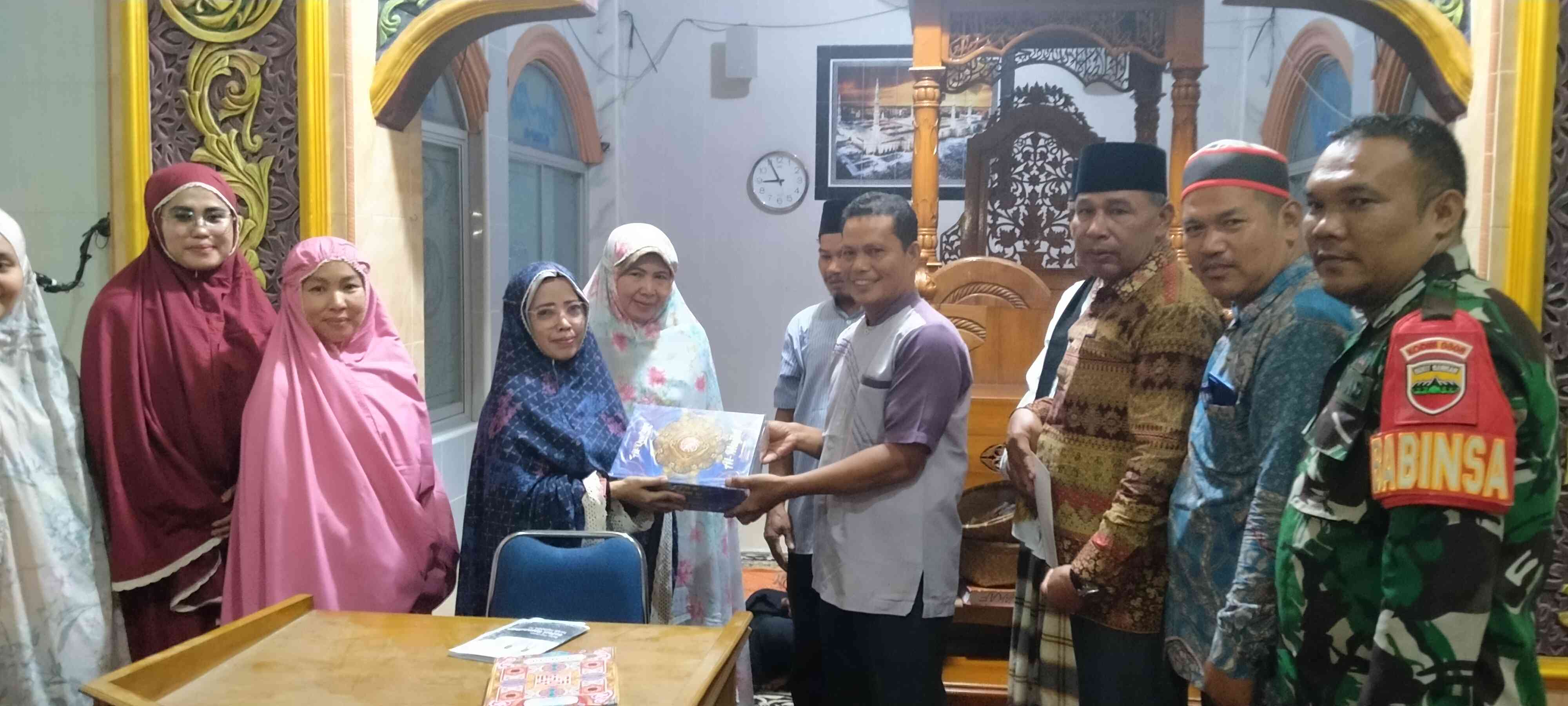 Sekretaris DPPKB Padang Pariaman menyerahkan bingkisan Quran ke pengurus Masjid Raya Baitul Makmur Sunua. (foto dokpri)