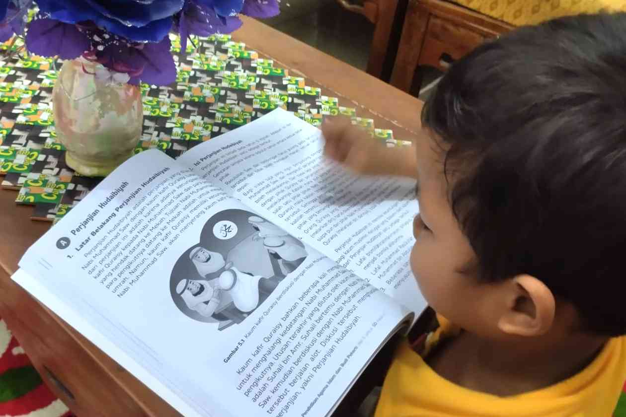 Si Kecil menyimak buku cerita tentang kisah Nabi Muhammad SAW. (foto Akbar Pitopang)
