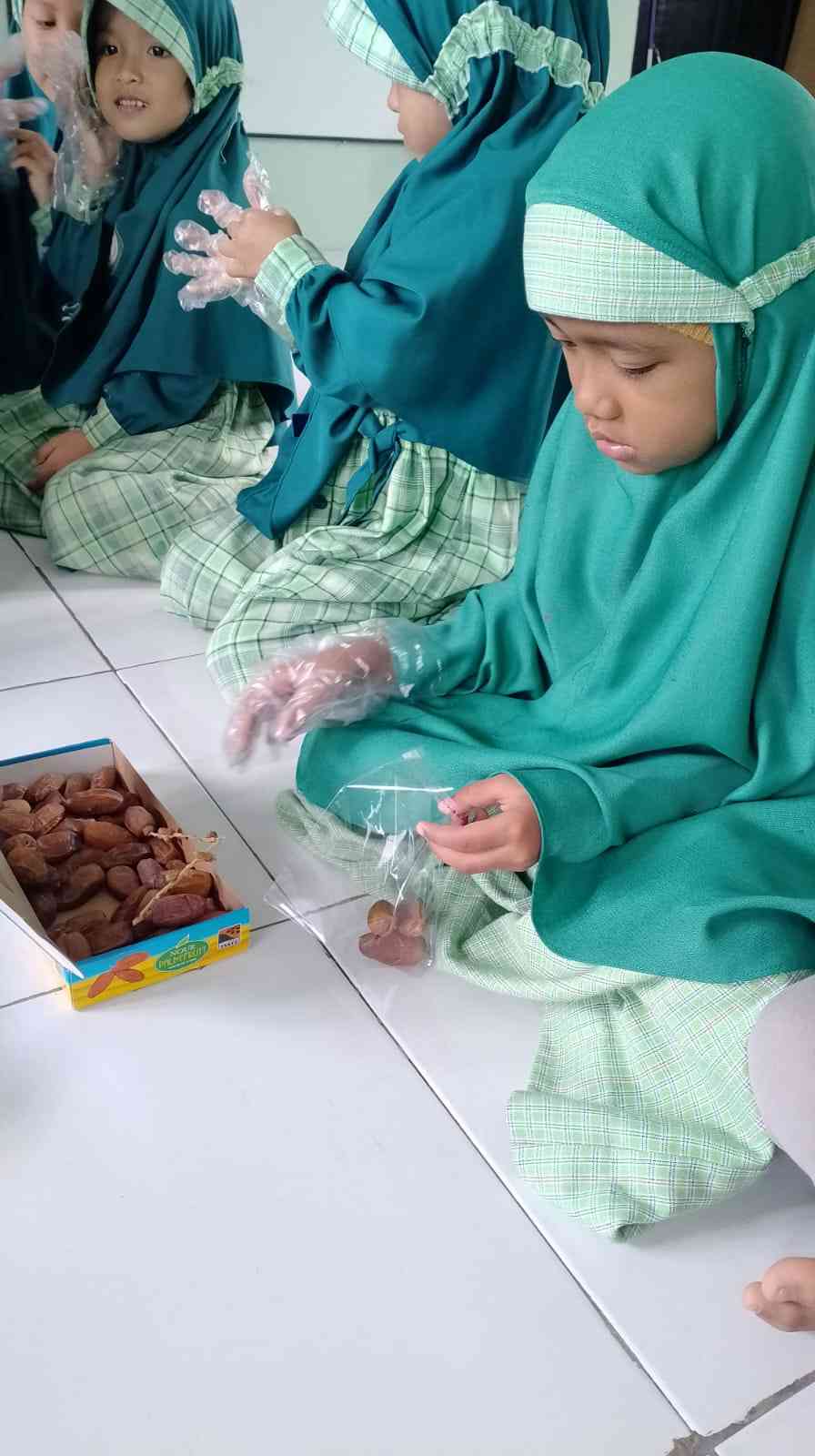 Para santri KBA Al Fatah mengemas kurma dibimbing Ustadzah | Foto: Umi Eva