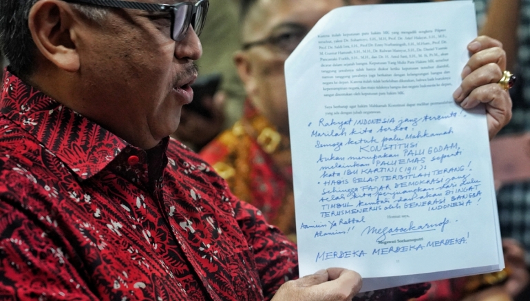 Sekretaris Jenderal PDI-P Hasto Kristiyanto menunjukkan tulisan tangan Ketua Umum PDI-P Megawati Soekarnoputri yang tertoreh pada surat amicus curiae dan diserahkan ke Mahkamah Konstitusi, Jakarta, Selasa (16/4/2024). Foto: KOMPAS/RONY ARIYANTO NUGROHO
