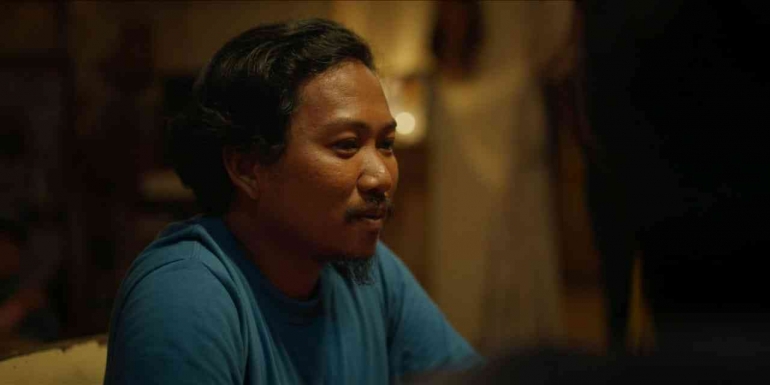 Basri tersenyum getir mendengar candaan vulgar saudara-saudaranya (Sumber gambar: Bioskop Online)Â