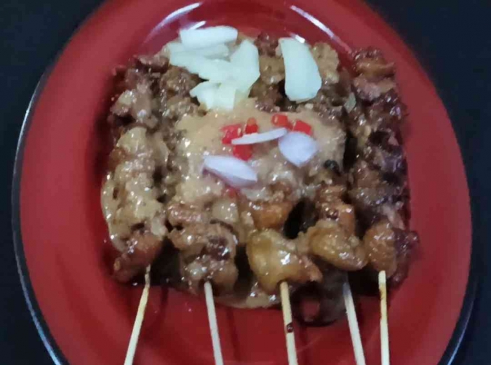 Sate ayam dan kulitnya yang sudah disiram bumbu kacang, dan ditaburi cabe dan bawang merah iris (dokpri)