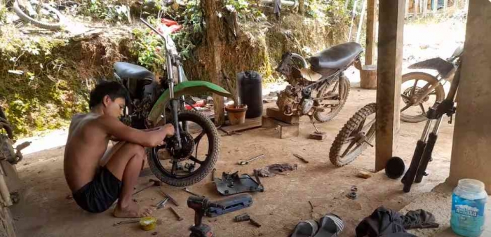 Pemuda Teguh sedang bekerja di bengkel motornya (dok foto: Greg Nafanu)