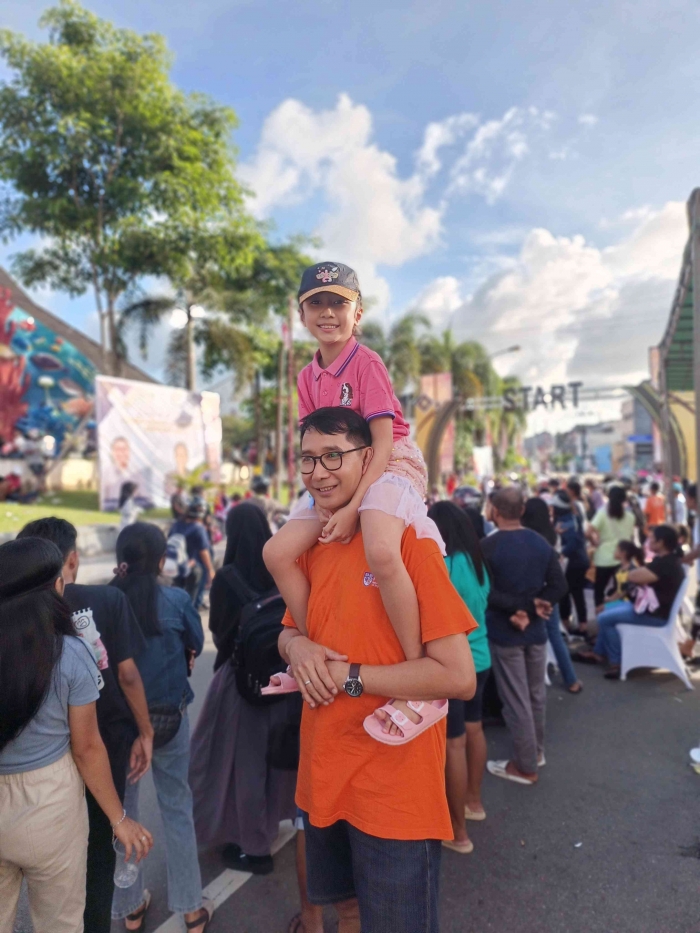 (Sumber pribadi) Kebahagiaan bapak dan anak di hari yang cerah saat lomba gerak jalan indah yang penuh dengan masyarakat kota ambon di jalan kota Ambo
