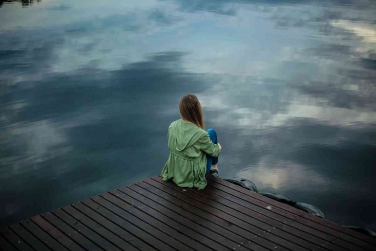 A girl sits alone (Photo by Keenan Constance: https://www.pexels.com/photo/woman-sitting-on-wooden-planks-2865901/)