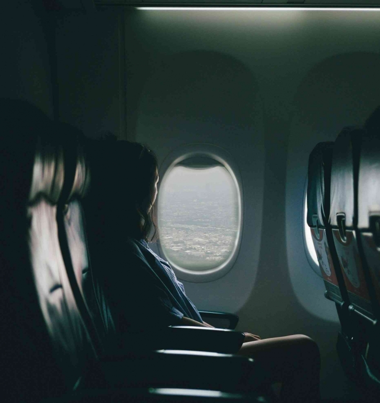 Foto seorang penumpang perempuan duduk dekat jendela pesawat (unsplash/Killian Pham)Â