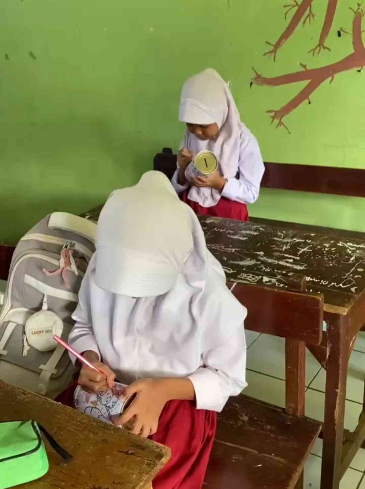Siswa mewarnai celengan.