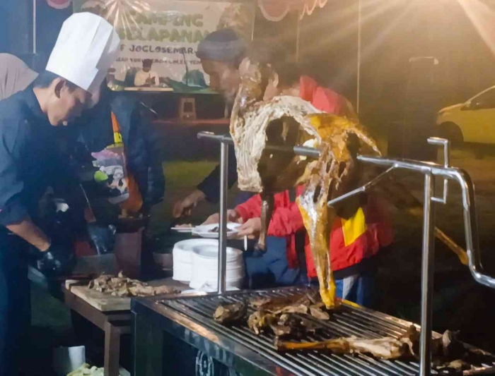 Seorang Chef sedang Membagikan kambing guling pada para peserta Camping Adventure Family Joglosemar (dokumentasi pribadi: Isti Yogiswandani)