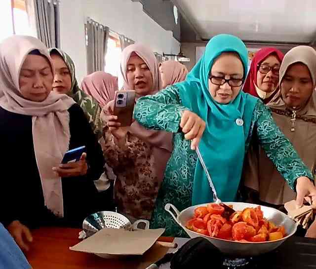 Bu Camat sedang mencoba mengaduk tomat bahan pembuat Torakur(dokumentasi pribadi: Isti Yogiswandani)
