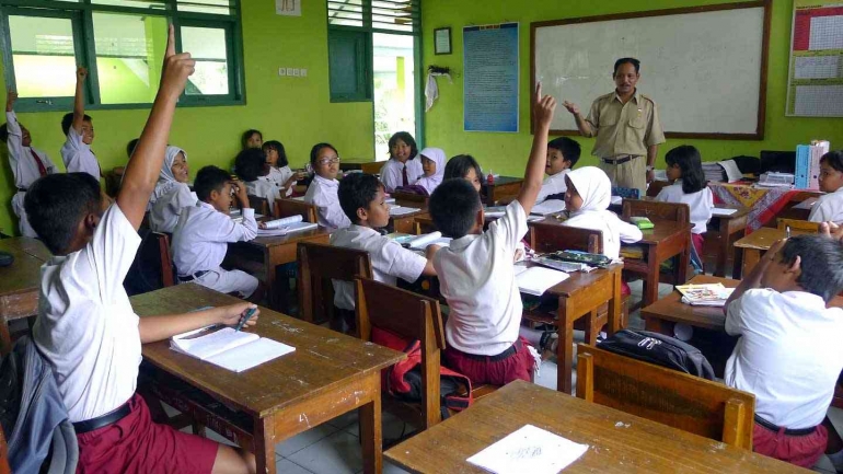 Guru mengajar siswa menggunakan laptop