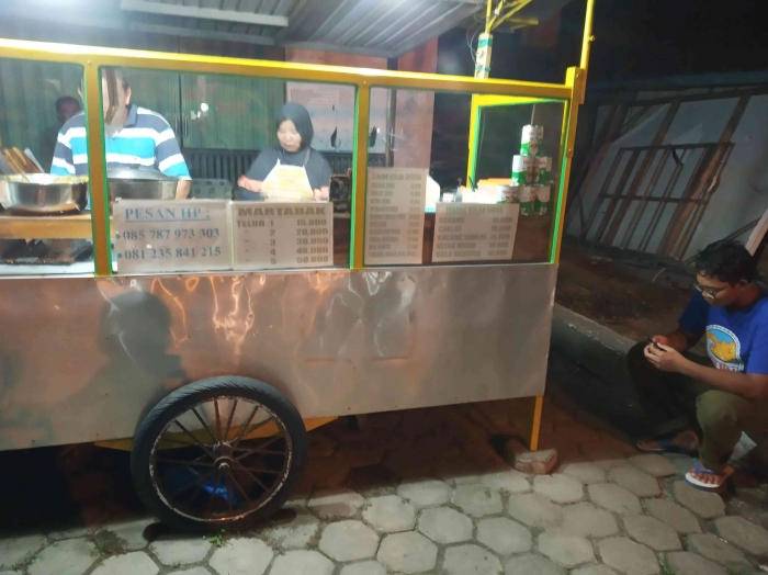 Anak ragil duduk di dekat penjual martabak (dokpri)