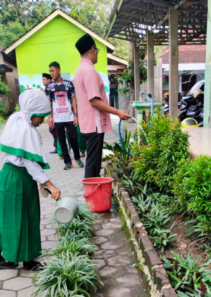 Pak kepsek mengajak para siswa membersihkan lingkungan sekolah dan menyiram tanaman (Dokumentasi MI Bahrul Ulum Buluh)