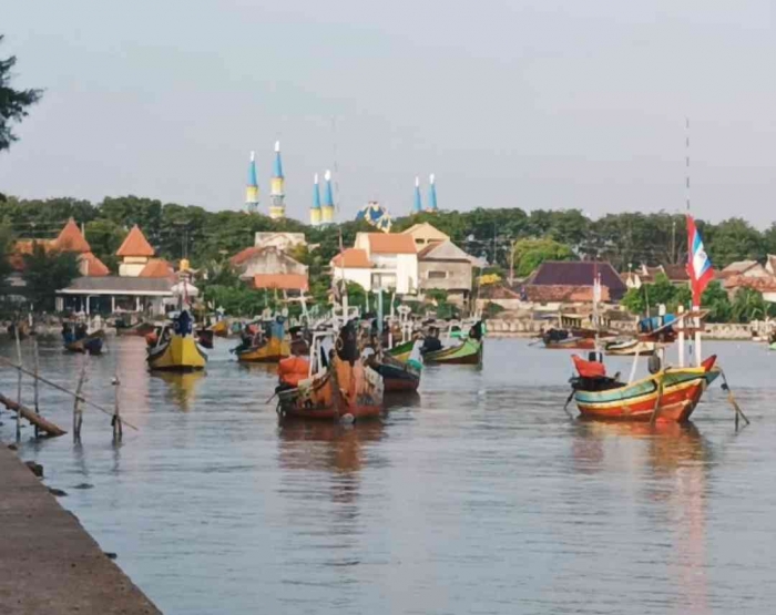 Kapal nelayan di Pantai Boom Tuban dengan latar belakang puncak masjid jami' (Dokumentasi pribadi: Isti Yogiswandani)