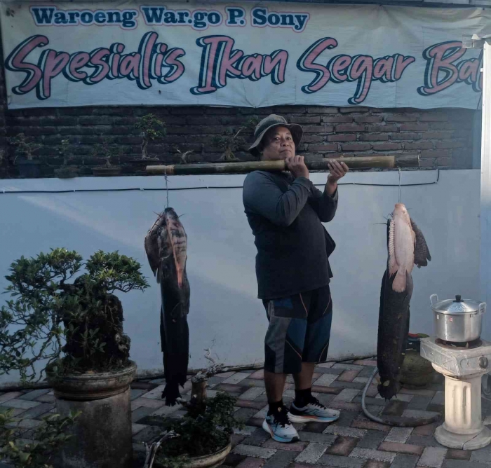 Mbah Mul berpose sambil memikul ikan lele dan nila jumbo(Dokumentasi pribadi: Isti Yogiswandani)
