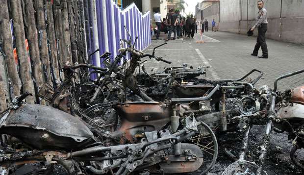 Petugas kepolisian melintas di depan bangkai motor yang dibakar massa di Sekolah Kristen Shekinah, Kota Temanggung, Jateng, Selasa (8/2). Aksi massa dipicu ketidakpuasan atas vonis lima tahun kepada terdakwa Antonius Richmond Bawengan dalam kasus penistaan agama/Kompasiana(tempo.co)