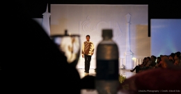 Salah satu peragawan dengan busana batik di Jogja Fashion Week 2012. Latar depan bayangan meja juri.