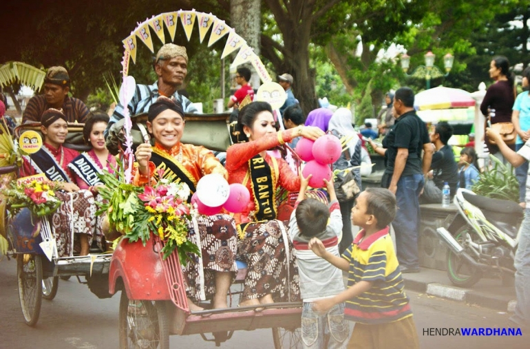 Dua orang anak kecil menghampiri becak yang ditumpangi Dimas dan Diajeng Bantul untuk meminta balon.