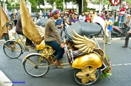 Tukang becak mengayuh becaknya yang dihias khusus untuk Hari Pariwisata Dunia.