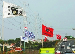 Bendera partai politik berukuran besar berkibar tertiup angin di pinggir jalan tol di kawasan Ancol, Jakarta Utara, Sabtu (4/10). Pemasangan bendera partai politik dan nomor urutnya di tiap sudut Jakarta yang tidak tertata rapi membuat pemandangan semrawut. (Kompas.com/Kompas/Agus Susanto)