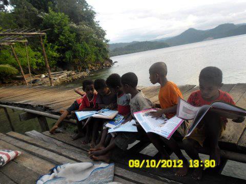 Anak-anak SD Kampung Tablasupa sedang membaca buku-buku bacaan dan pelajaran dari kegiatan Bakti Sosial Madridista Jayapura