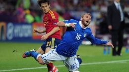 Daniele De Rossi (R) of Italy falls to the ground after battling David Silva (L) of Spain for the ball during their UEFA EURO 2012 final