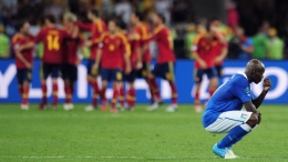 Mario Balotelli (R) of Italy reacts Spain celebrate the fourth goal scored by Juan Mata during their UEFA EURO 2012 final