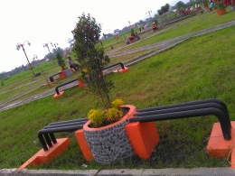 Tempat duduk yang ditengahi oleh pot bunga di Taman Kota Soreang